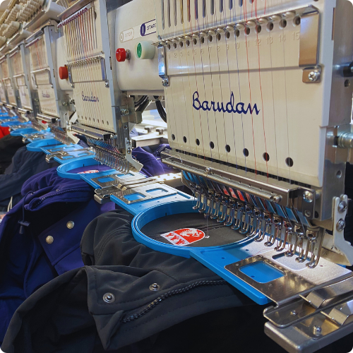 Embroidery machine stitching logo on flame-retardant safety uniform.