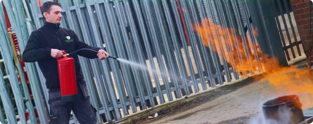 An engineer using a water fire extinguisher in a live fire extinguisher training course