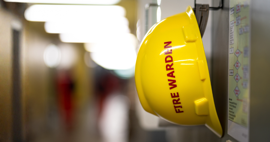 A yellow fire warden workwear hat hung up in a corridor