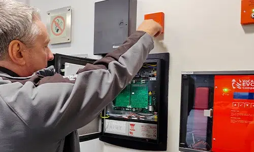 Engineer servicing fire alarm